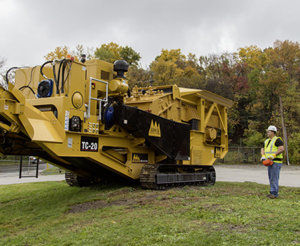 Man next to IROCK stone crusher with HBC radio control in hand.